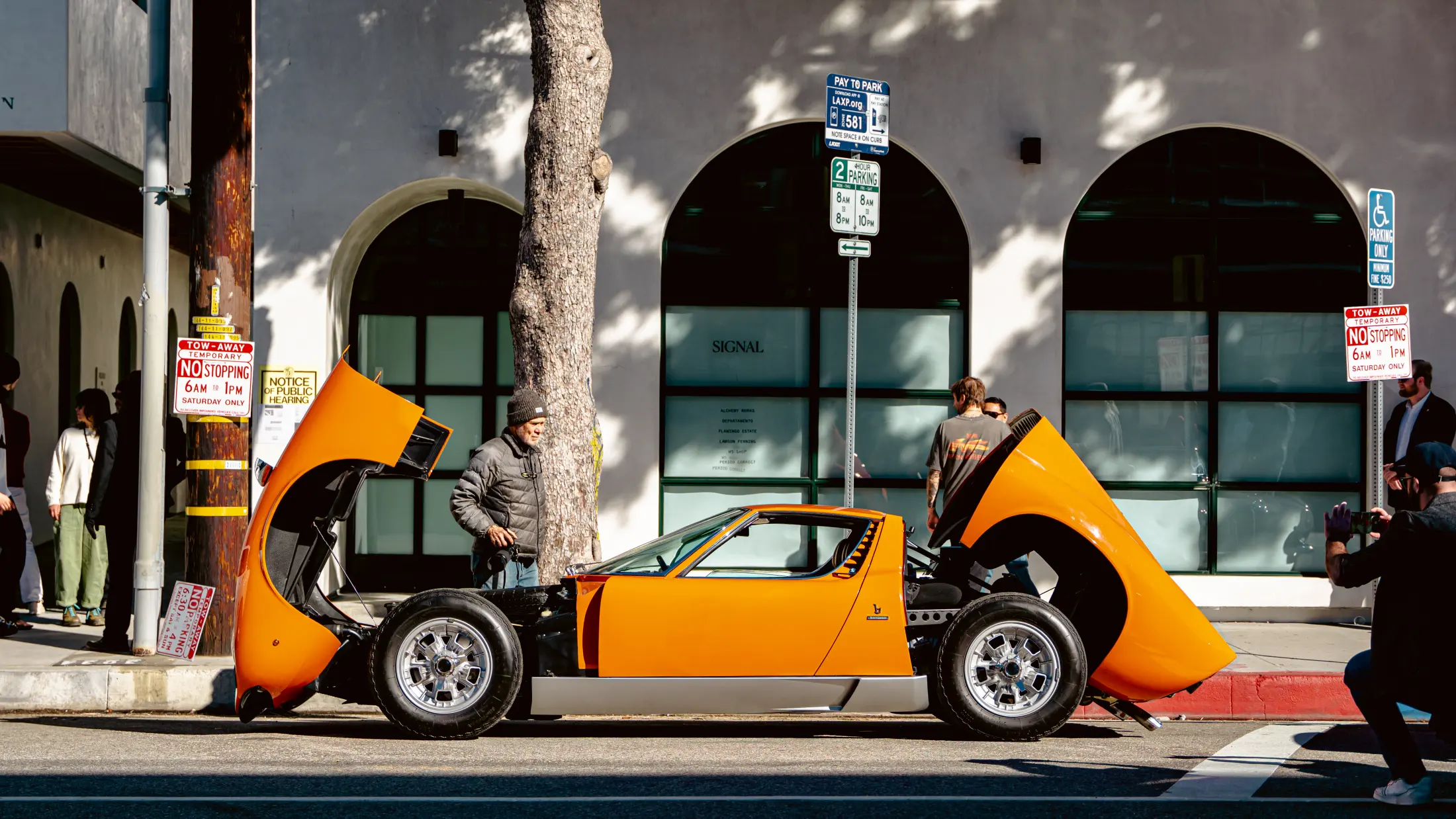 An orange sports car with its panels open outside Signal on Traction Ave